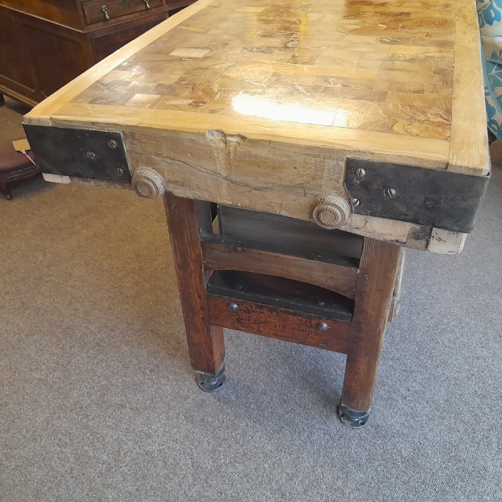An antique butchers block featuring a thick end-grain timber top reinforced with iron corner brackets on a wooden stand with a lower shelf. View II