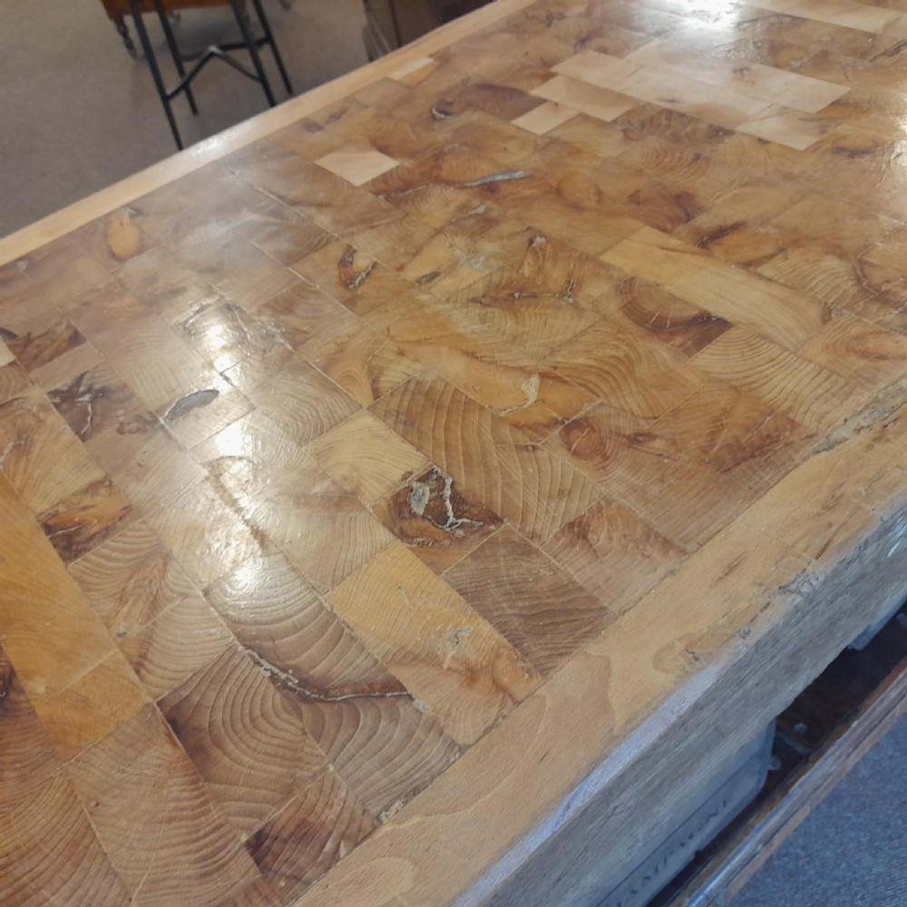 An antique butchers block featuring a thick end-grain timber top reinforced with iron corner brackets on a wooden stand with a lower shelf. View V