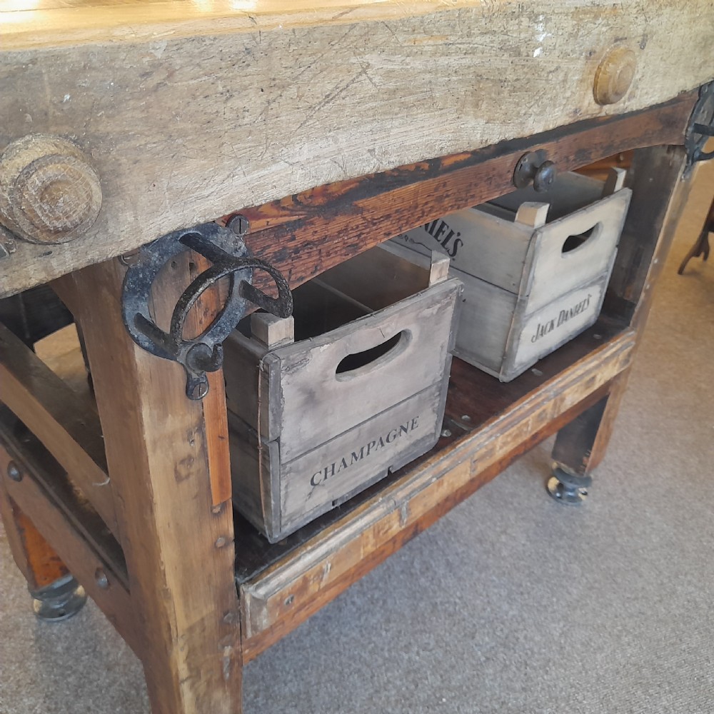 An antique butchers block featuring a thick end-grain timber top reinforced with iron corner brackets on a wooden stand with a lower shelf. View VI