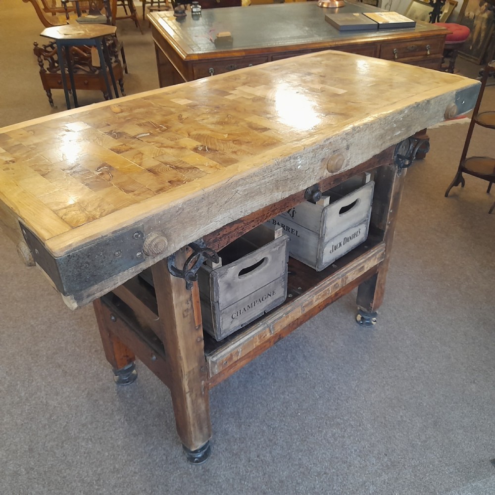An antique butchers block featuring a thick end-grain timber top reinforced with iron corner brackets on a wooden stand with a lower shelf. View VII