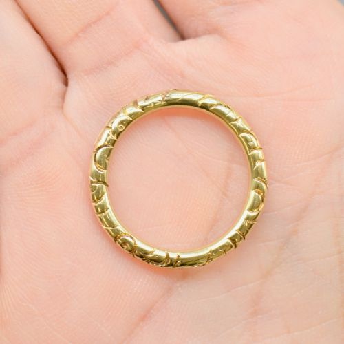 fig 1. An antique 14ct yellow gold circular split ring featuring continuous hand-engraved geometric pattern along its outer edge.