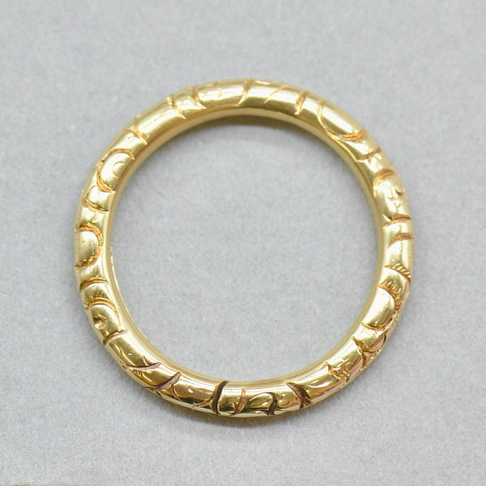 An antique 14ct yellow gold circular split ring featuring continuous hand-engraved geometric pattern along its outer edge.