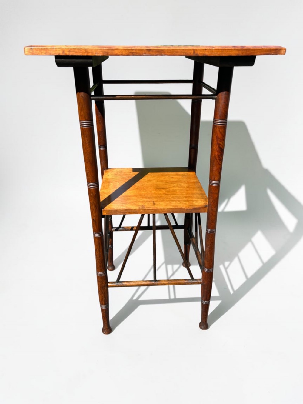 A square walnut side table in the Aesthetic Movement style featuring turned legs with incised rings, an undertier shelf, and spindled lower bracing. View II