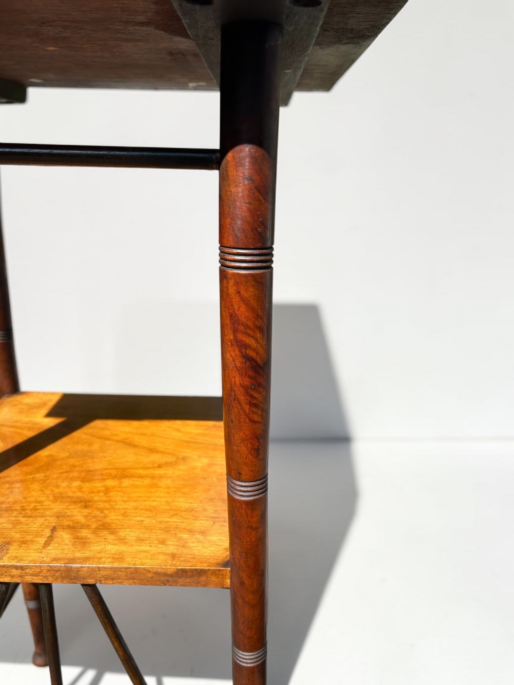 A square walnut side table in the Aesthetic Movement style featuring turned legs with incised rings, an undertier shelf, and spindled lower bracing. View IV