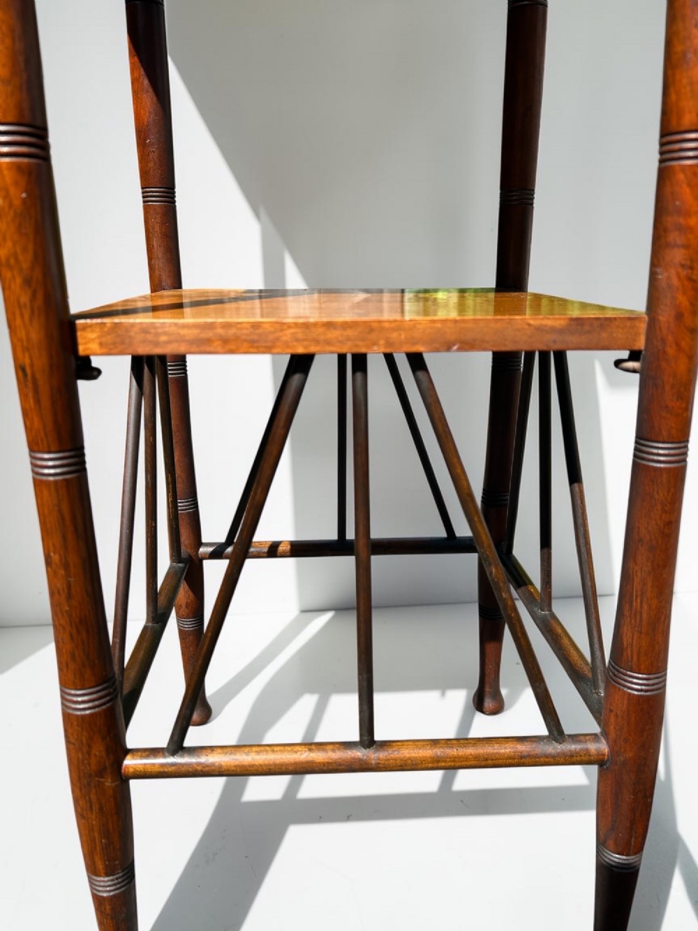 A square walnut side table in the Aesthetic Movement style featuring turned legs with incised rings, an undertier shelf, and spindled lower bracing. View VI