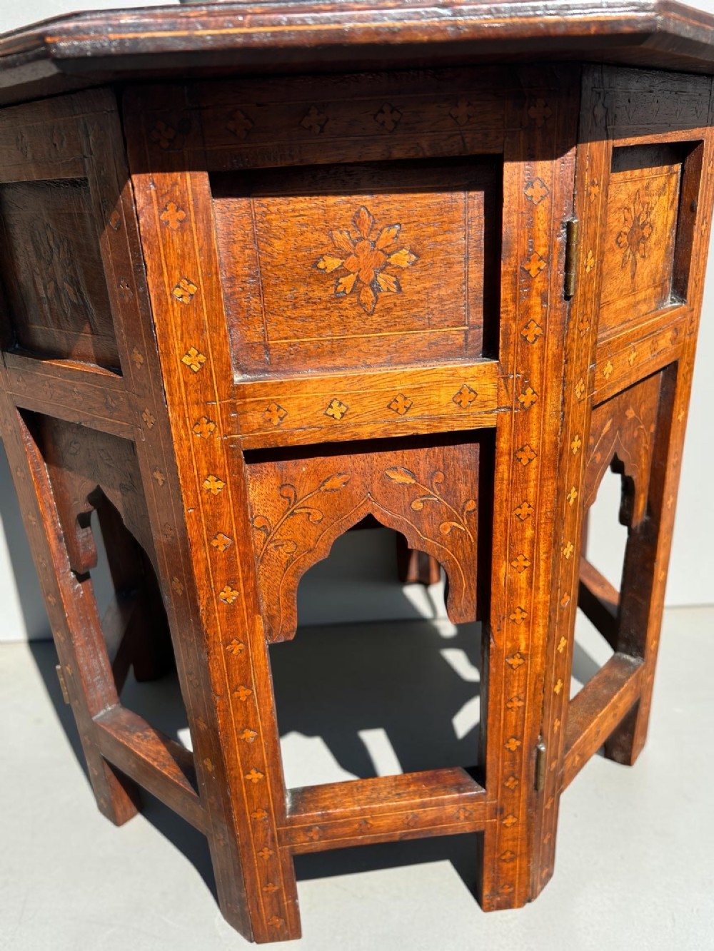 An octagonal Anglo-Indian wooden side table featuring intricate floral marquetry inlay across the top and an openwork arched apron base. View II