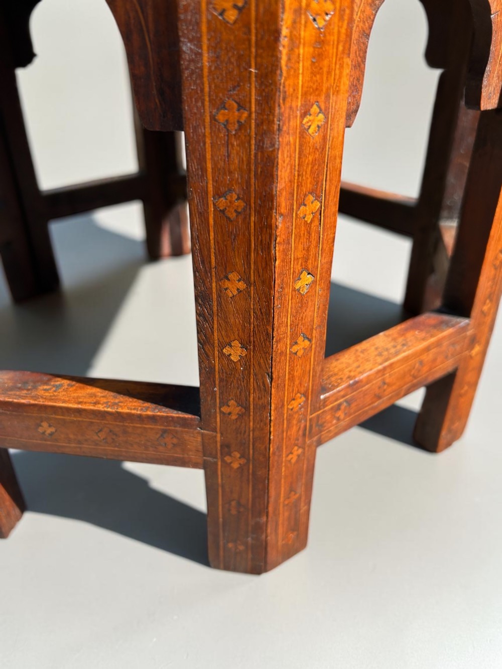 An octagonal Anglo-Indian wooden side table featuring intricate floral marquetry inlay across the top and an openwork arched apron base. View III