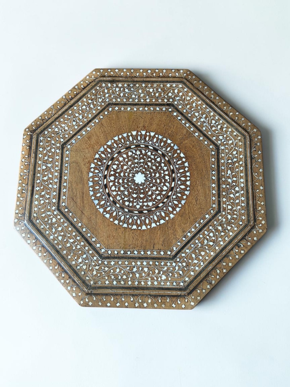 An octagonal wooden occasional table featuring dense white floral and geometric bone inlay across the top and arched panel legs. View II