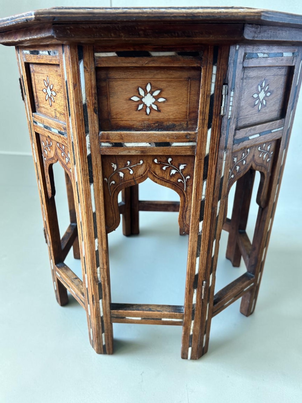 An octagonal wooden occasional table featuring dense white floral and geometric bone inlay across the top and arched panel legs. View III