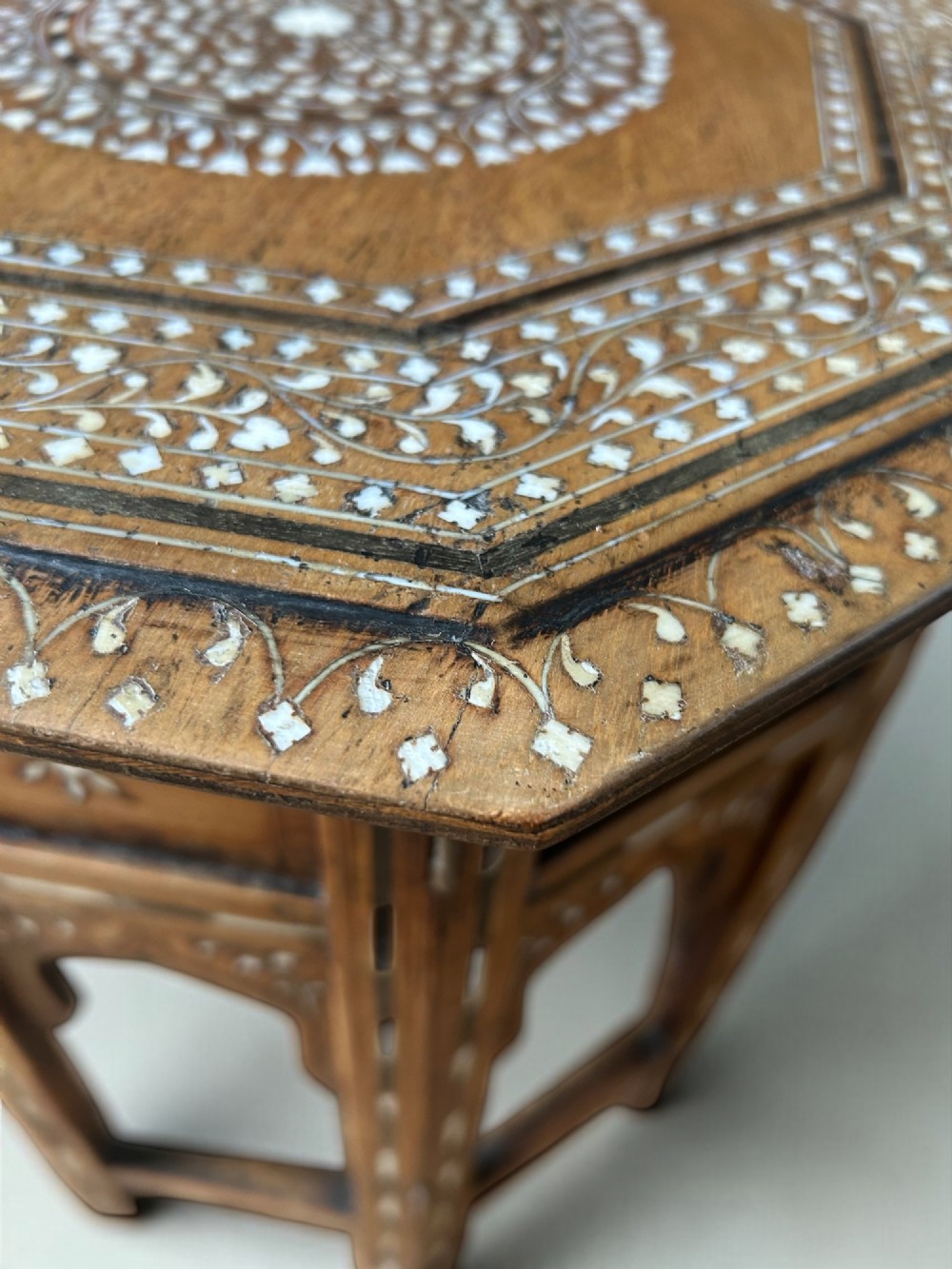 An octagonal wooden occasional table featuring dense white floral and geometric bone inlay across the top and arched panel legs. View IV
