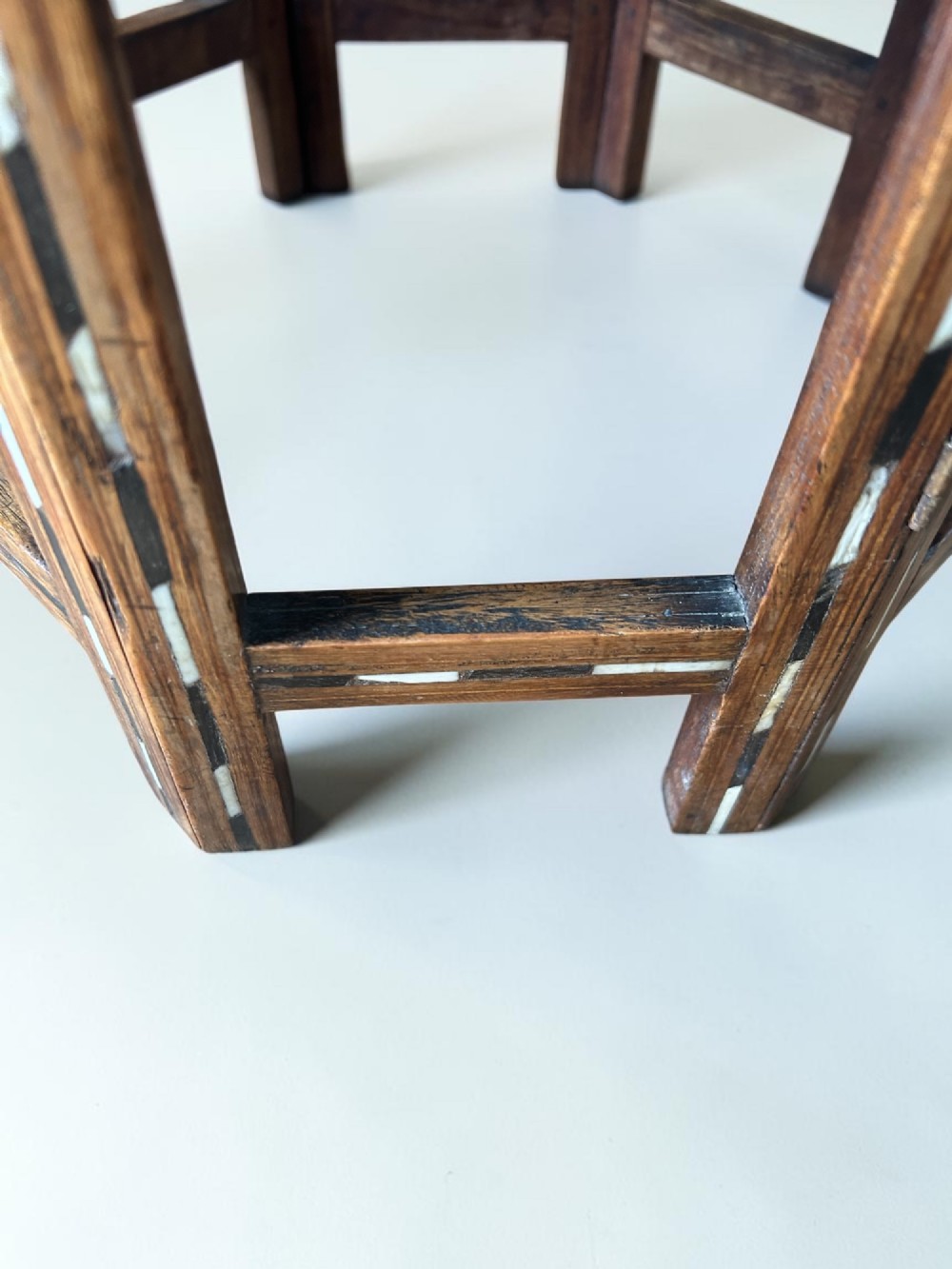 An octagonal wooden occasional table featuring dense white floral and geometric bone inlay across the top and arched panel legs. View V