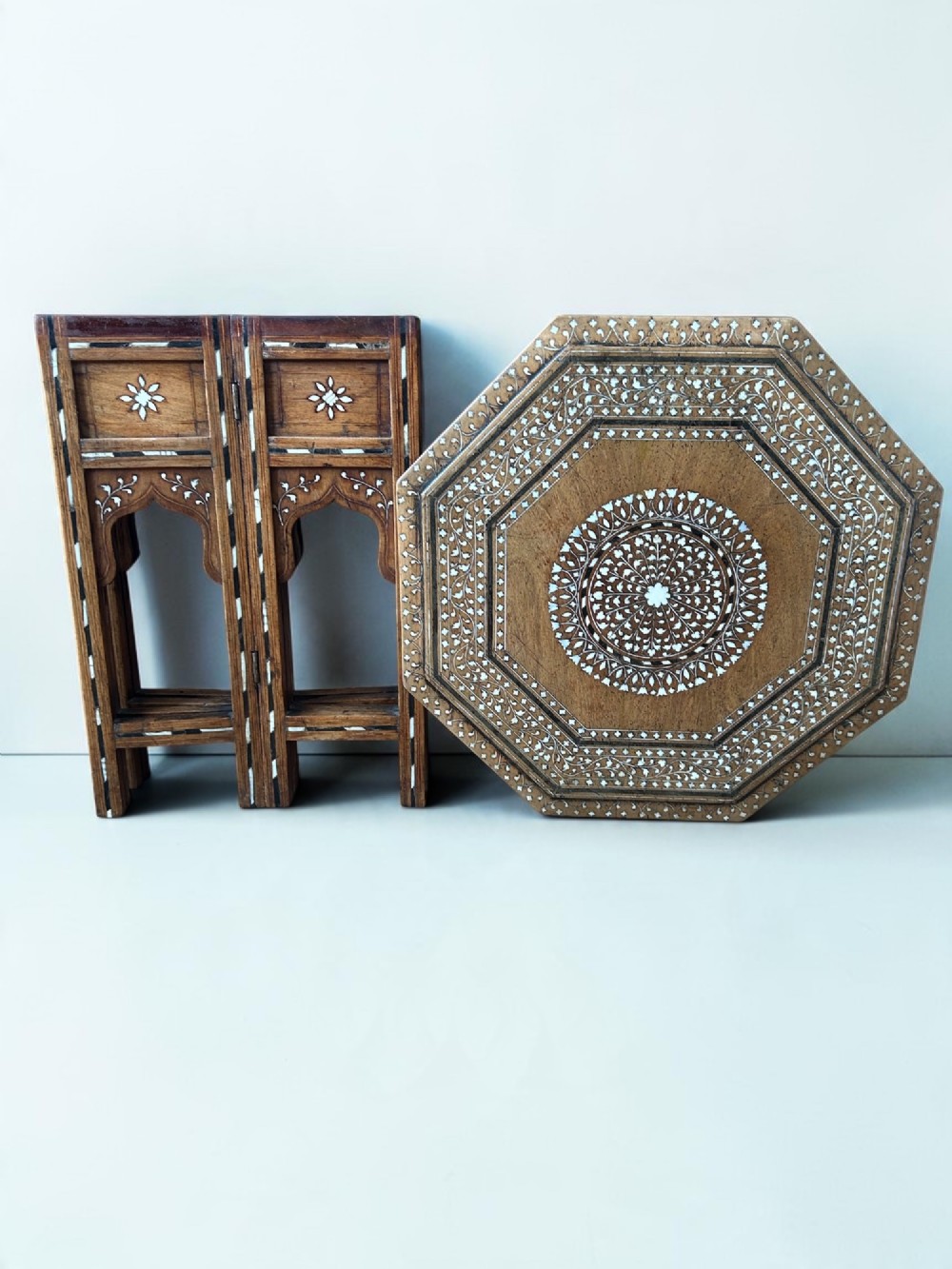 An octagonal wooden occasional table featuring dense white floral and geometric bone inlay across the top and arched panel legs. View VI