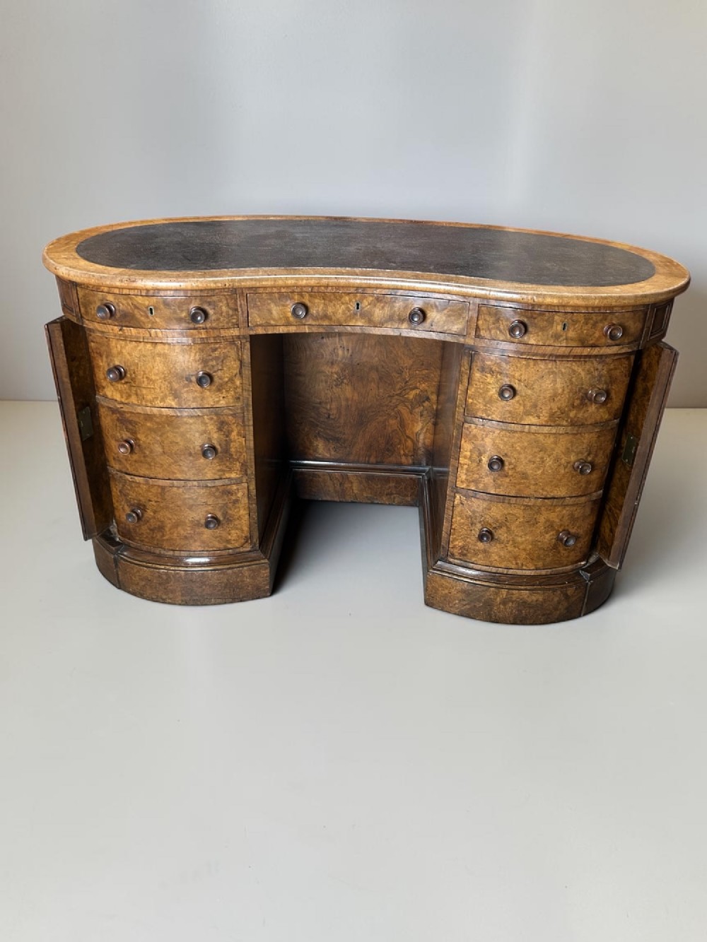 A 19th-century freestanding kidney-shaped desk crafted from warm brown burr walnut with a dark leather inset top and dual drawer pedestals. View II