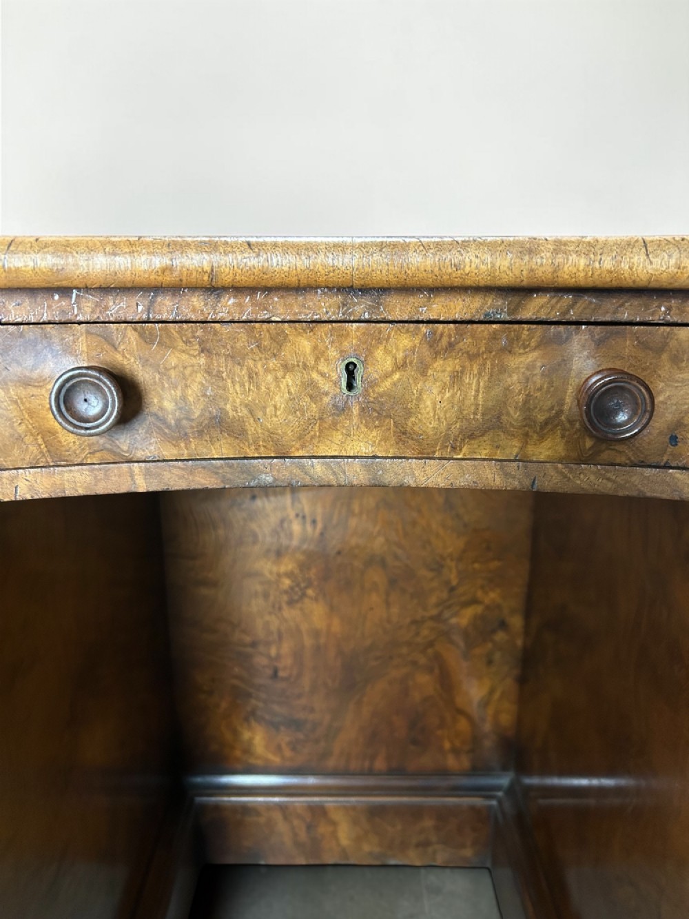 A 19th-century freestanding kidney-shaped desk crafted from warm brown burr walnut with a dark leather inset top and dual drawer pedestals. View V