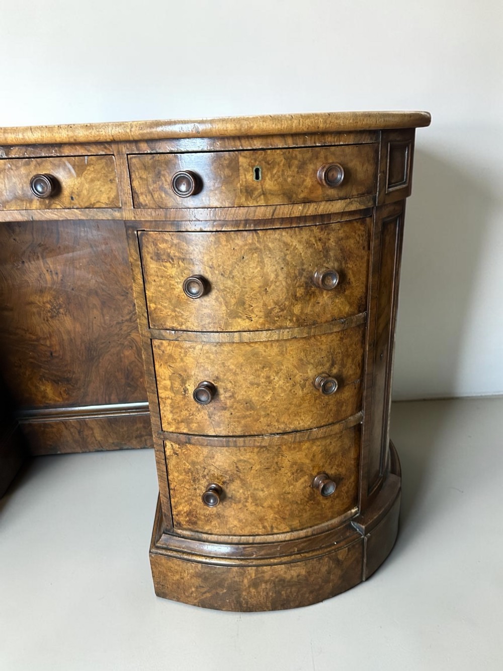 A 19th-century freestanding kidney-shaped desk crafted from warm brown burr walnut with a dark leather inset top and dual drawer pedestals. View VI