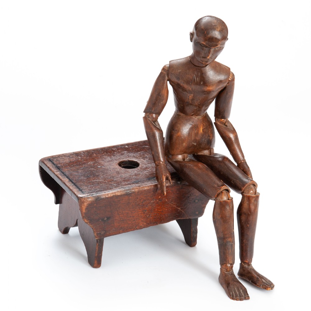 A low rectangular dark elm wooden stool featuring a central hand aperture and cut-out slab end supports.