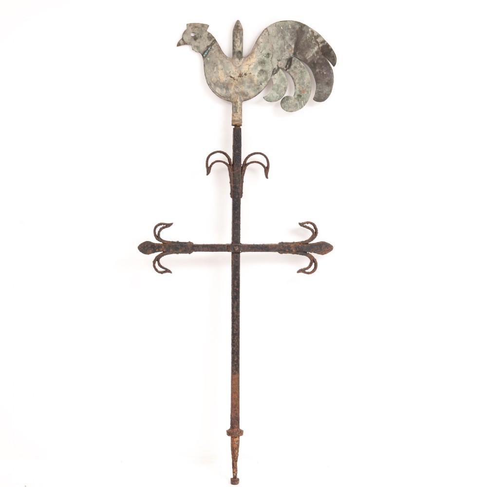 An antique weathered metal cockerel weather vane featuring a green copper rooster finial mounted on a rusted wrought iron central spire.
