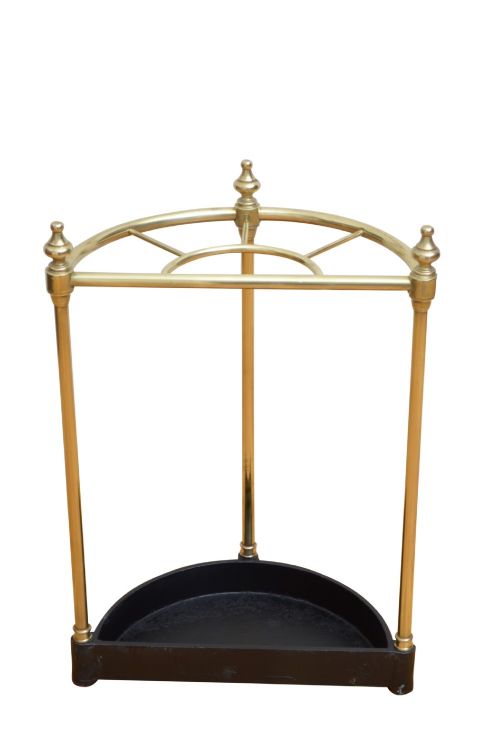 fig 1. An Edwardian brass umbrella stand featuring a demi-lune frame, urn finials, three vertical posts, and a black cast iron drip tray with a dogtooth pattern.
