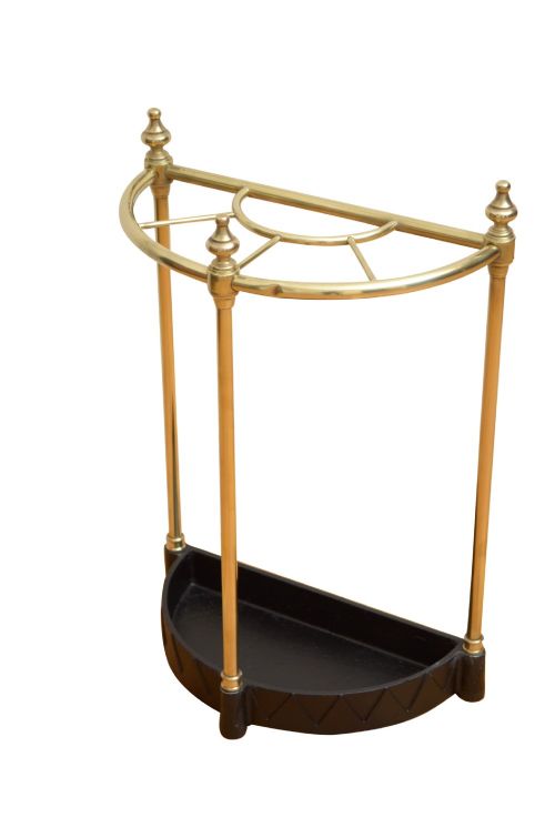 An Edwardian brass umbrella stand featuring a demi-lune frame, urn finials, three vertical posts, and a black cast iron drip tray with a dogtooth pattern. View IV