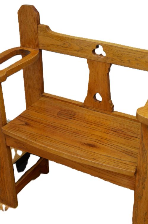 fig 2. A golden oak Arts and Crafts hall seat featuring a central backboard with a trefoil cut-out, flat armrests with circular stick apertures, and sturdy rectangular uprights.
