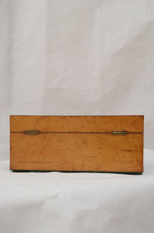 An open Victorian birds eye maple wooden box featuring scrollwork tulipwood inlay on the front and a green patterned paper interior lining. View IX
