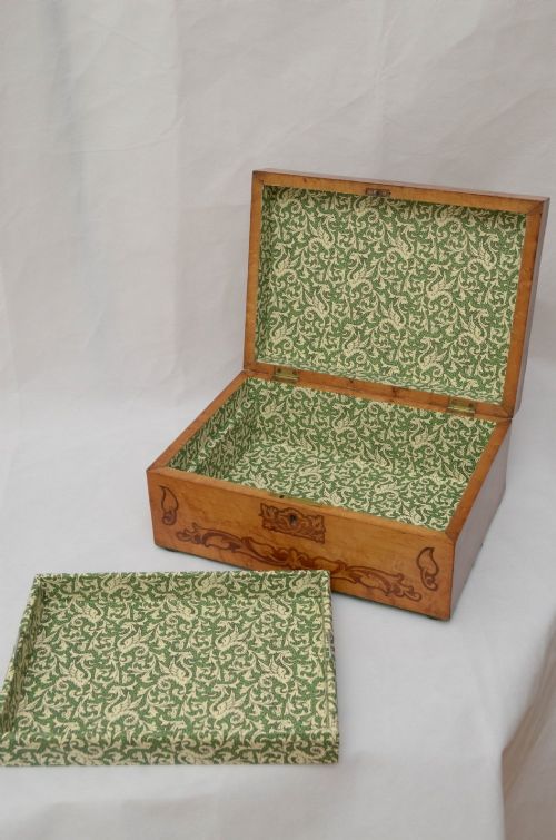 An open Victorian birds eye maple wooden box featuring scrollwork tulipwood inlay on the front and a green patterned paper interior lining. View XII