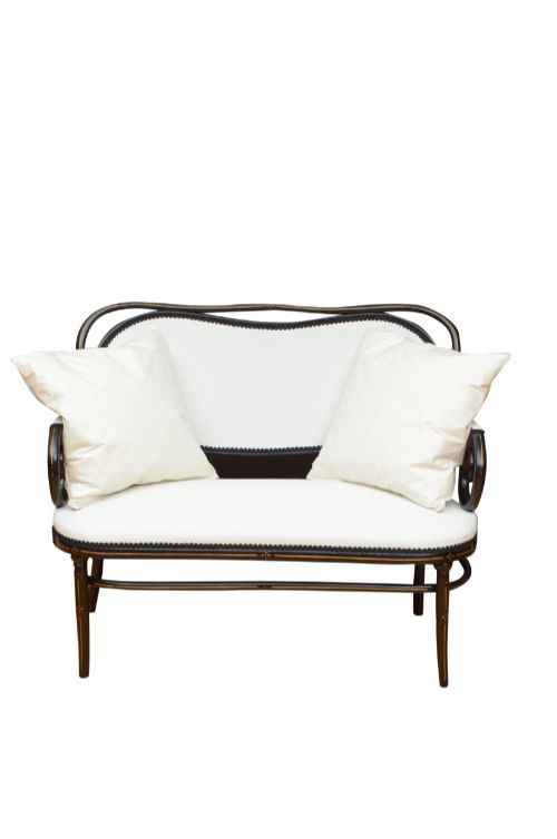 fig 2. An ebonised steam-bent wood settee with a cream upholstered backrest and seat cushion.