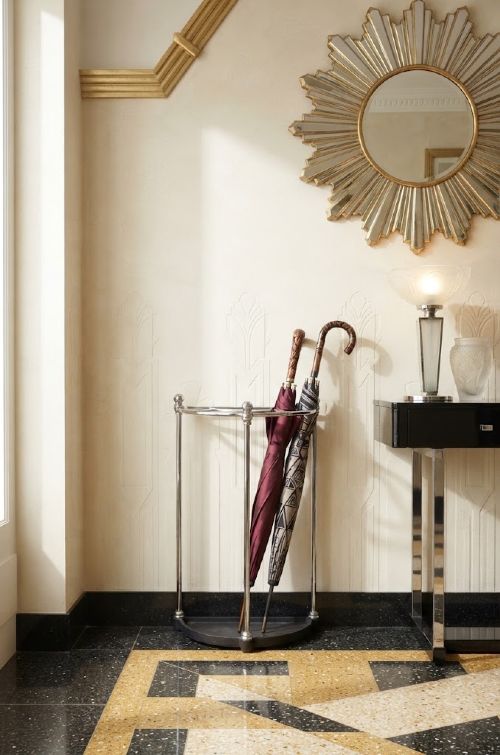 An Art Deco demi-lune nickel-plated umbrella stand featuring a semi-circular top frame with five divisions, vertical support rods with spherical finials, and a black cast iron drip tray base. View VIII