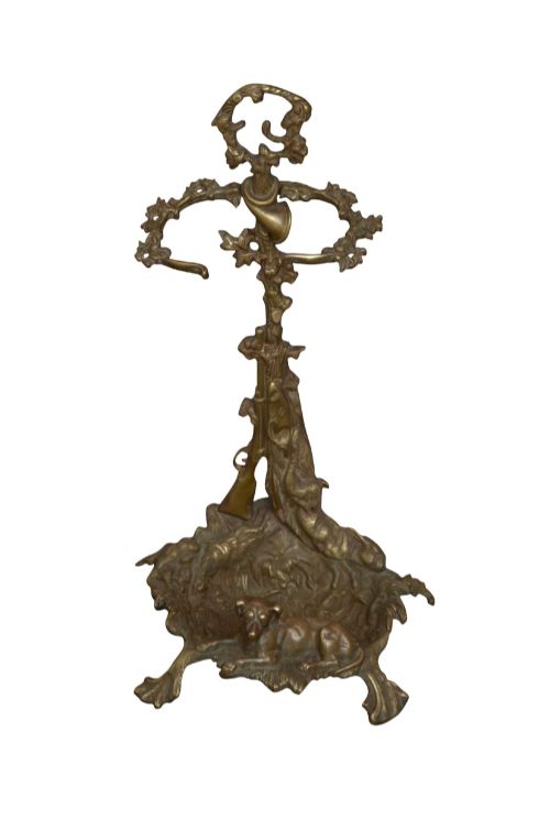 fig 1. A cast brass stick stand featuring relief motifs of a resting hunting dog, crossed rifles, and foliage with a drip pan base.