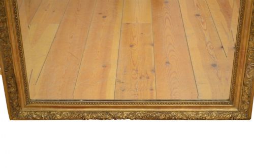 A large nineteenth-century French giltwood overmantel mirror featuring an ornate carved cresting motif and a arched top rectangular frame. View IV