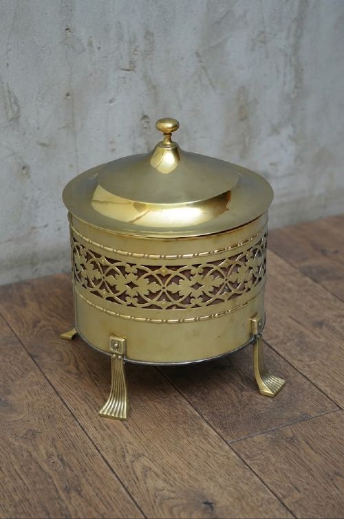 A cylindrical Edwardian polished brass coal bucket featuring a fretwork band, domed lid with finial, and three cast fluted feet. View II