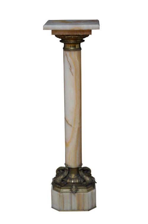 fig 2. A tall cylindrical cream and amber onyx column featuring gilt bronze ormolu mounts at the top and base, set on a square plinth.