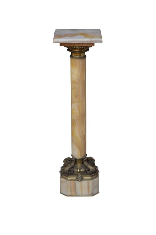 fig 1. A tall cylindrical cream and amber onyx column featuring gilt bronze ormolu mounts at the top and base, set on a square plinth.