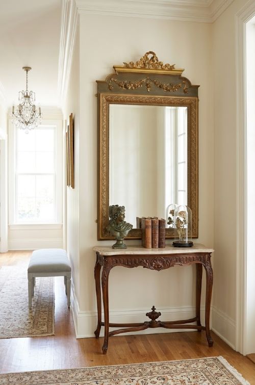 A large rectangular French wall mirror featuring a gilded wood frame, an olive green painted frieze decorated with carved floral swags, and an ornate ribbon bow crest. View III