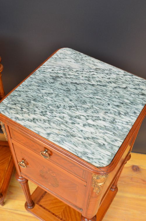 A pair of antique satinwood bedside cabinets with green marble tops, fluted turned legs, and decorative parquetry wood inlays. View X