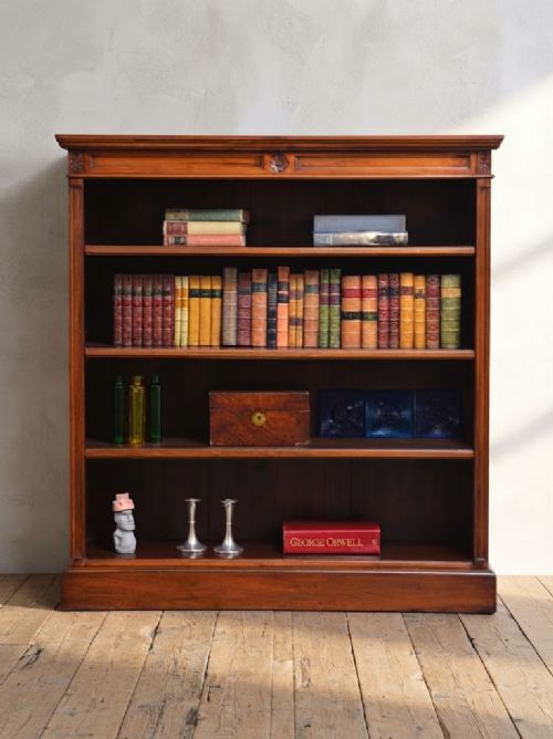 A late Victorian open walnut bookcase featuring a carved rosette frieze, moulded top cornice, adjustable shelves, and a solid plinth base. View II