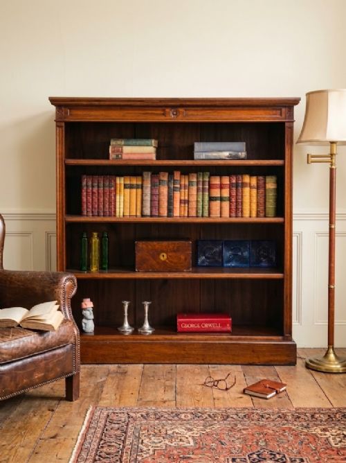 A late Victorian open walnut bookcase featuring a carved rosette frieze, moulded top cornice, adjustable shelves, and a solid plinth base. View VI
