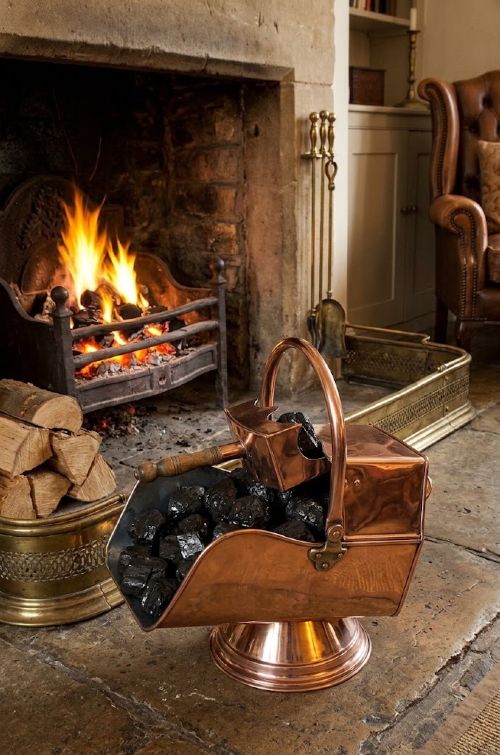An Arts and Crafts copper coal helmet scuttle on a pedestal base with a matching hand shovel featuring a turned wooden handle. View V