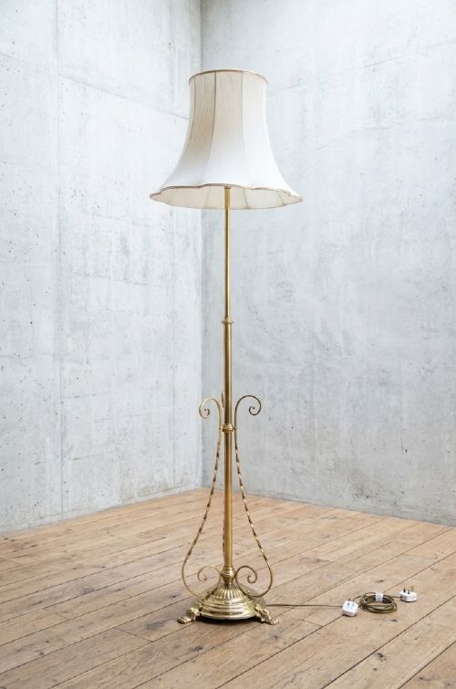 An English Arts and Crafts brass standard lamp featuring a telescopic height-adjustable stem, ornamental scroll braces, a fluted circular base, and a flared white fabric shade. View III