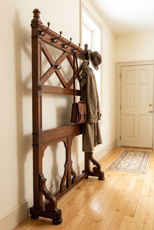 A Gothic Revival solid oak freestanding coat stand featuring upper hooks, carved diamond lattice fretwork, turned finials, and a shaped trestle base. View III