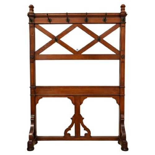 A Gothic Revival solid oak freestanding coat stand featuring upper hooks, carved diamond lattice fretwork, turned finials, and a shaped trestle base. View II