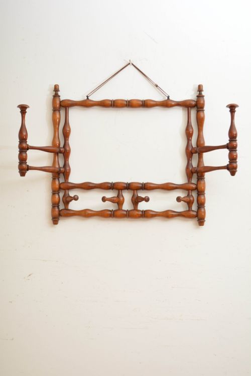 fig 1. A French antique bobbin-turned wooden coat rack featuring swivelling upper hooks and fixed lower pegs suspended by a hanging cord.