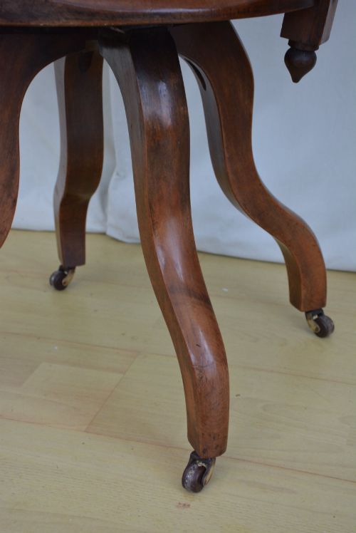 fig 3. A 19th-century Victorian walnut revolving desk chair featuring a curved backrest with turned spindles, a contoured solid seat, and splayed legs on castors.