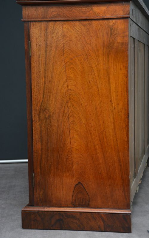 fig 1. A low George IV rosewood cabinet bookcase featuring a central door with a brass wire mesh grille flanked by two glazed doors, topped with a brass gallery rail.