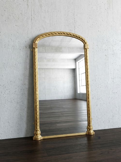 A tall arched gilded pier mirror featuring rope-twist carving, square corner block details, and reflective glass with light foxing. View XIII