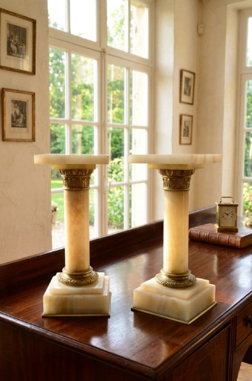 A pair of low Victorian cream onyx columns featuring ornate brass ormolu capitals and square tiered bases. View II