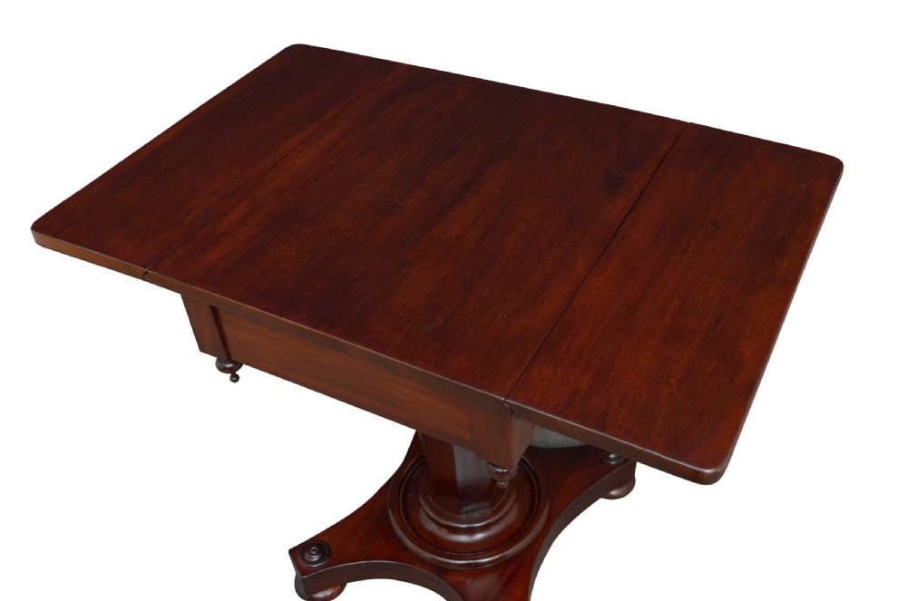 An antique William IV mahogany drop-leaf table featuring a rectangular top with hinged side flaps, supported by a central column stem and a quadform plinth base on bun feet. View III
