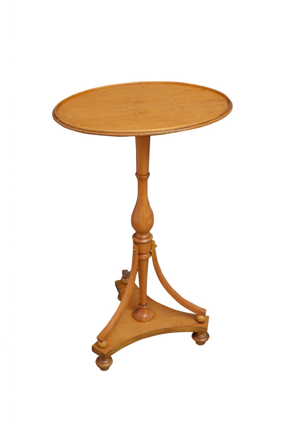 A light wood satinwood occasional table featuring an oval top, a turned central pedestal, and a tripod base with bun feet.