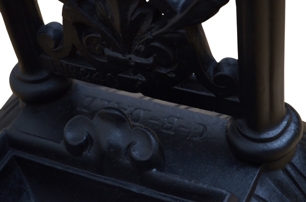 An ornate black cast iron umbrella and walking stick stand featuring openwork scroll panels, vertical pillars, and a compartmentalised base drip tray. View V