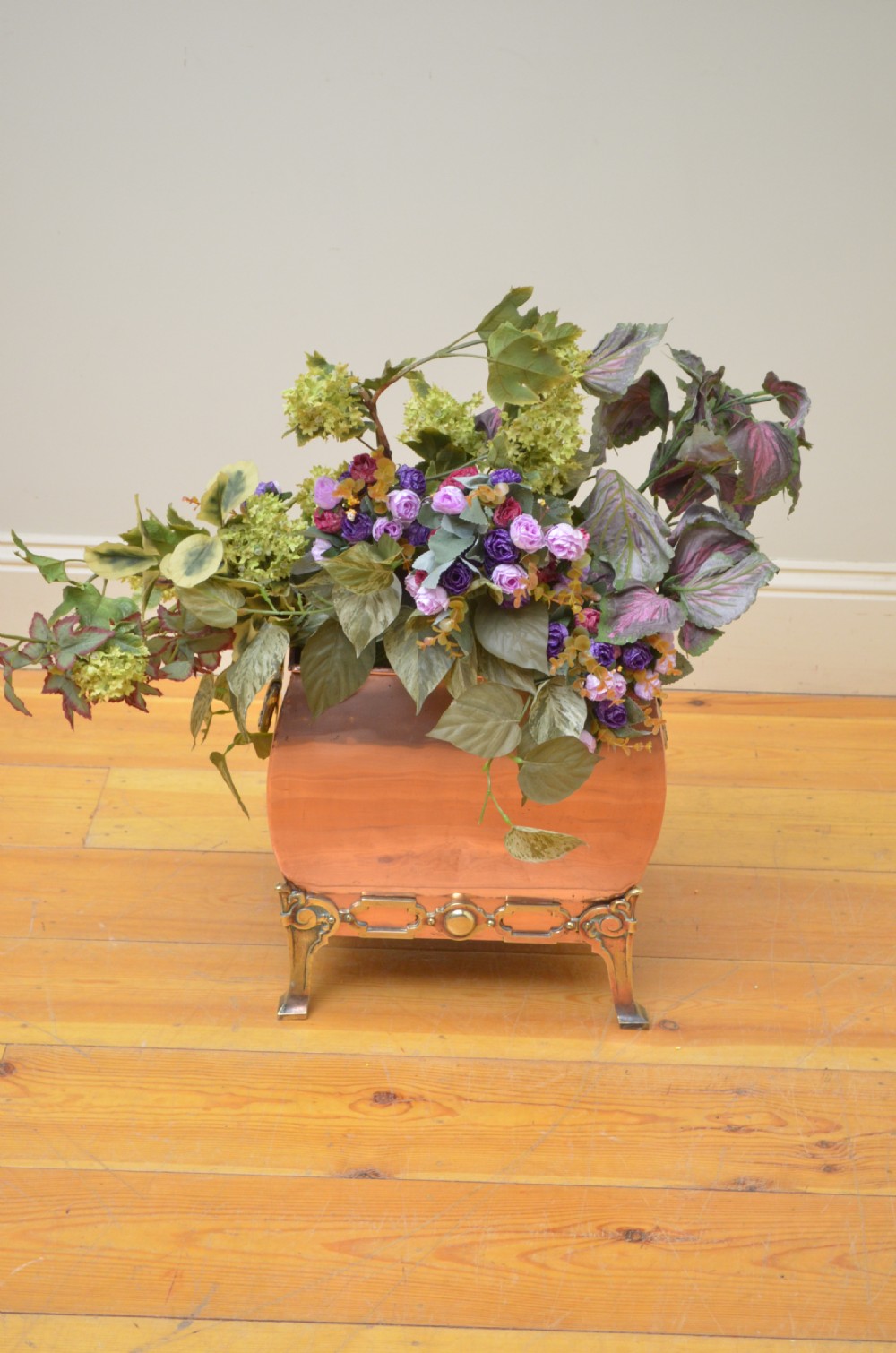 An angled view of a rectangular brass coal bin with a domed lid, riveted seams, side ring handles, and small round feet. View VIII